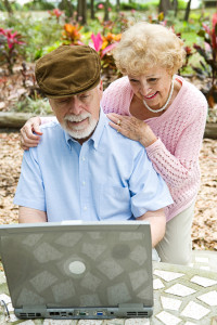 Happy senior couple using their laptop computer outdoors. Focus on husband.